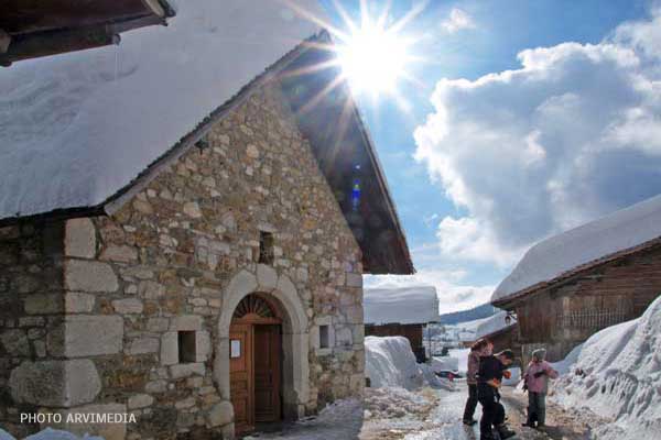 village traditionnel savoyard avec sa chapelle sous la neige